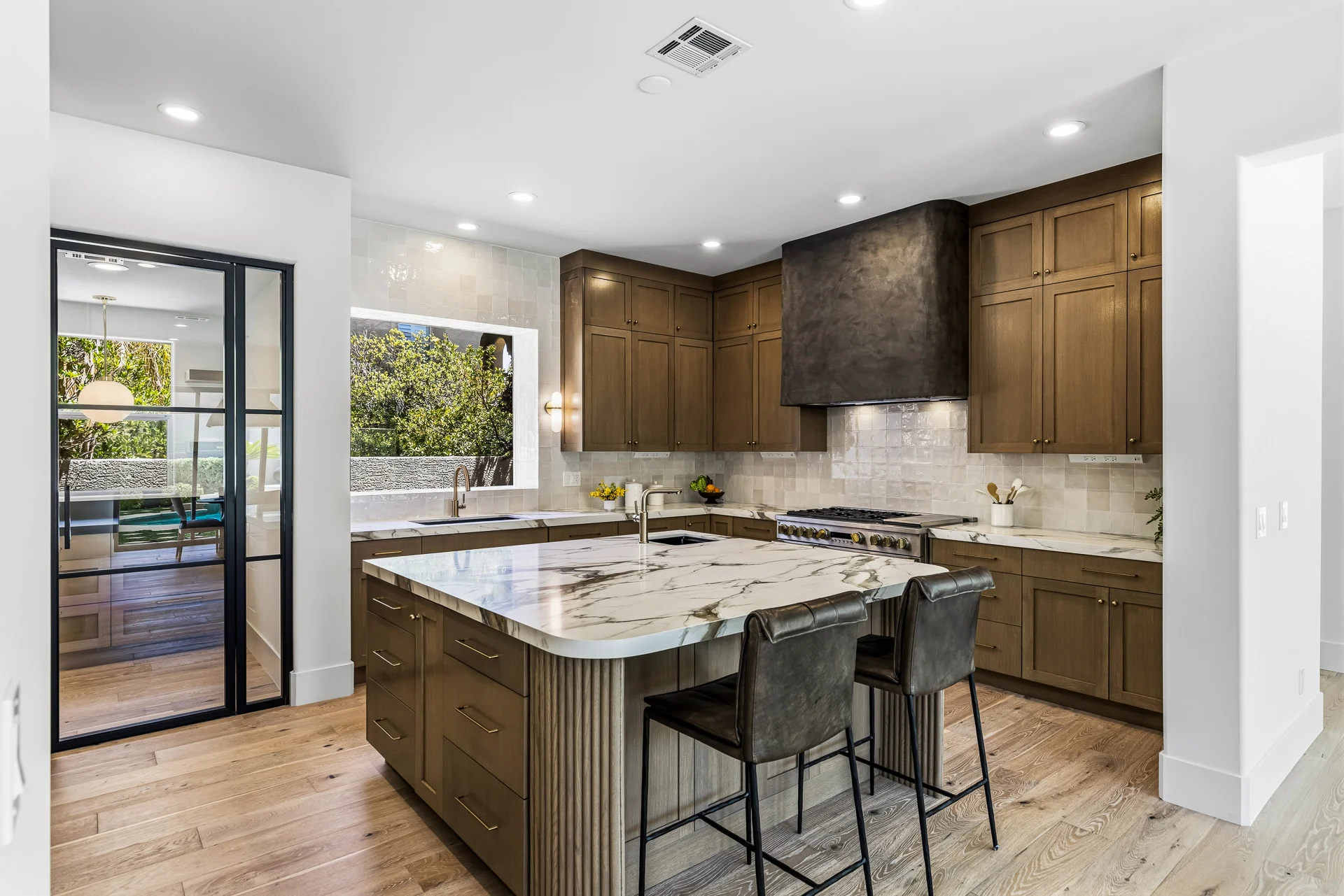 Kitchen with a marble island, wood cabinetry and a plaster range hood